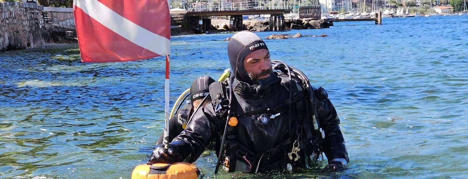 Un istruttore subacqueo Bolzano Sub in superficie con la bandiera segnasub in mano Diventare subacquei nel migliore dei modi